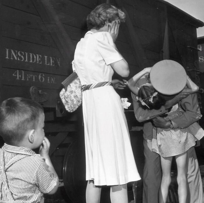 Black and white somber photo of a family reunion at a train station, capturing emotional history moments.
