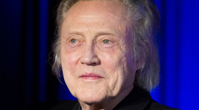 Elderly man with gray hair and light skin in front of a blue background, contemplating how would you call them.