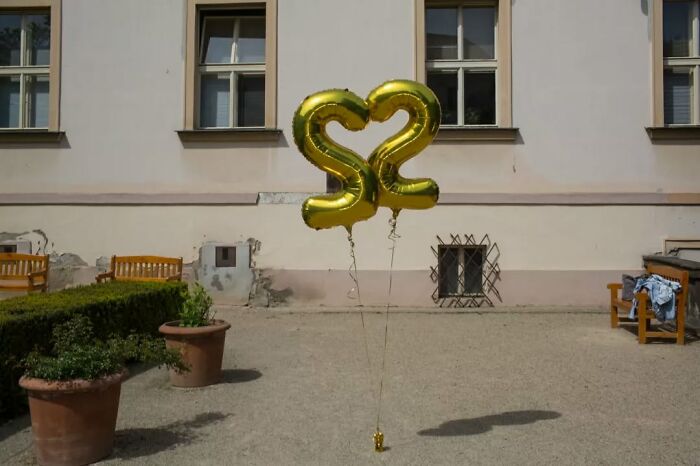 Golden balloon numbers 3 and 2 forming a heart shape, a street photographer capturing serendipitous moments in everyday life.