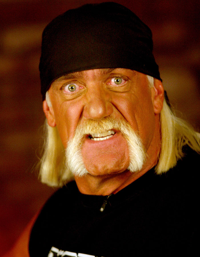 Close-up of WWE legend Hulk Hogan with his signature mustache and bandana, expressing intensity in a dark setting. - 1
