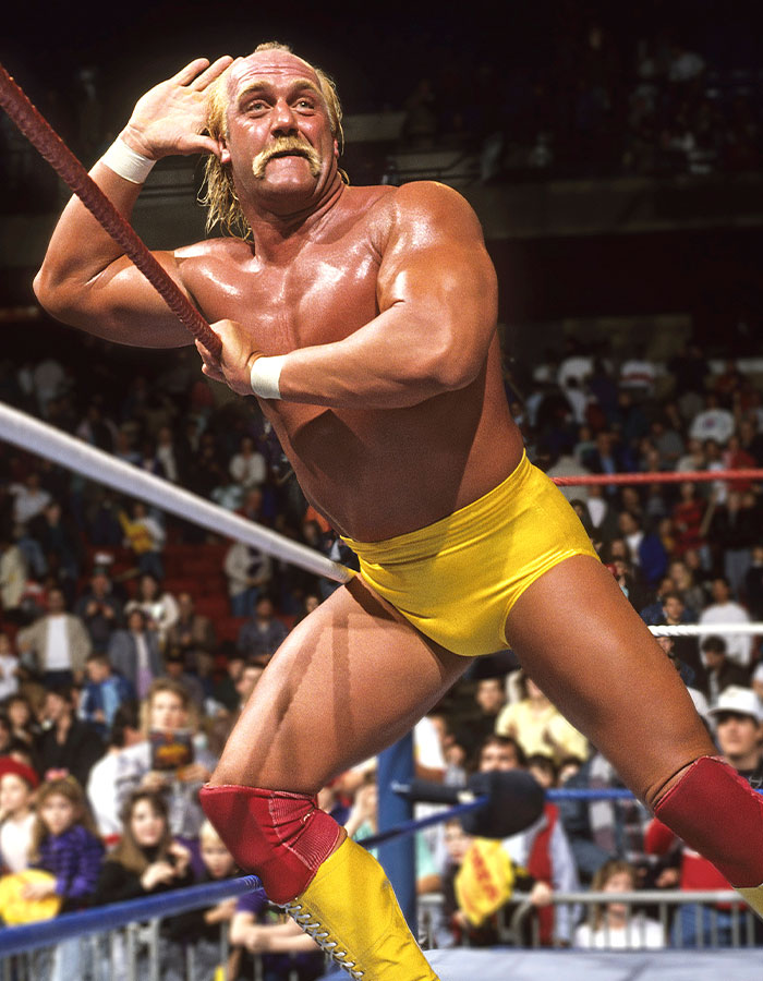 WWE legend Hulk Hogan in yellow trunks posing in the ring with fans watching, related to his cause of passing at 71. - 7