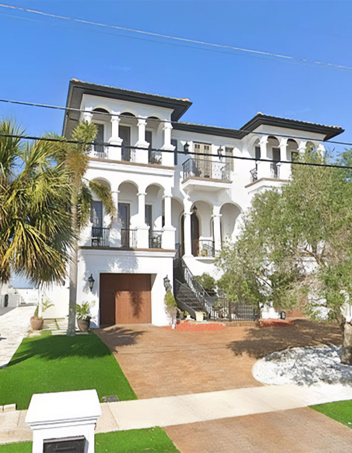 White Mediterranean-style mansion with arched balconies and a palm tree under clear blue sky, linked to WWE legend Hulk Hogan. - 5