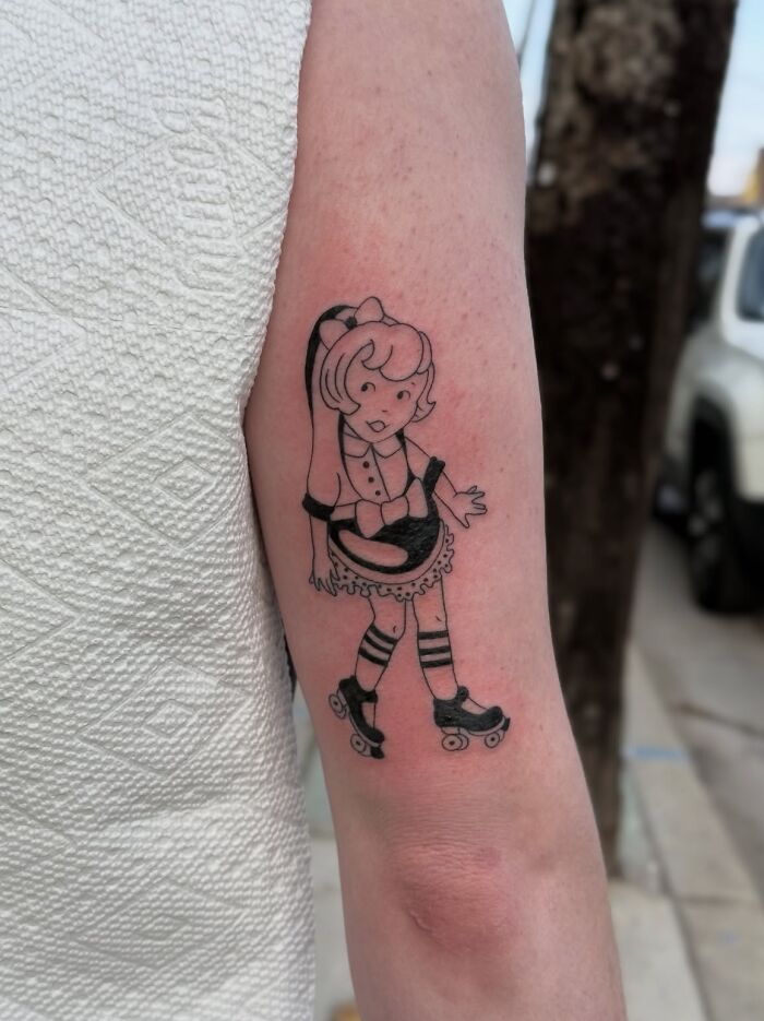 Tattoo of a cartoon girl with pigtails roller skating on a forearm, showcasing one of the best tattoos liked by many.
