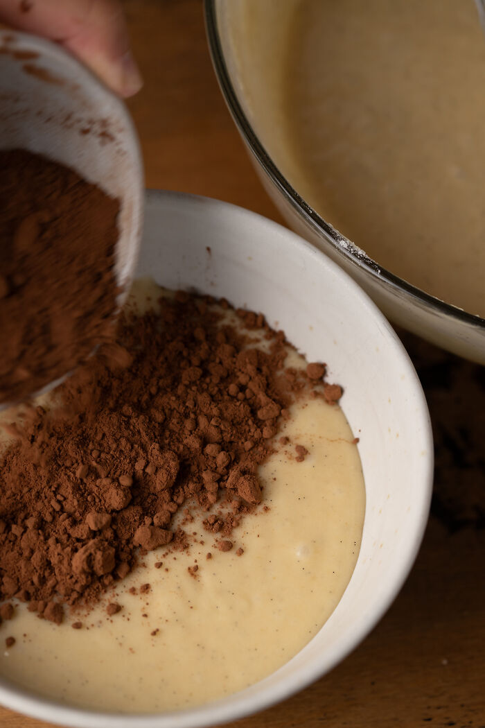 Baking childhood cake batter in a bowl with cocoa powder being added for a family remedy after hospital trip. - 8