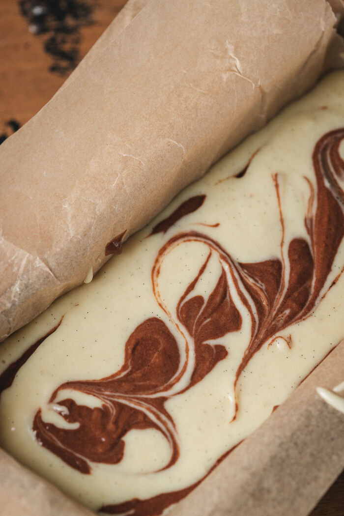 Marble cake batter in a parchment-lined pan, illustrating baking a childhood cake as an unexpected family remedy. - 10
