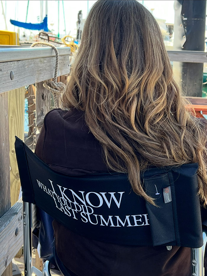 Person with long hair sitting on director chair showing back, related to Sarah Michelle Gellar and Jennifer Love Hewitt premiere event.
