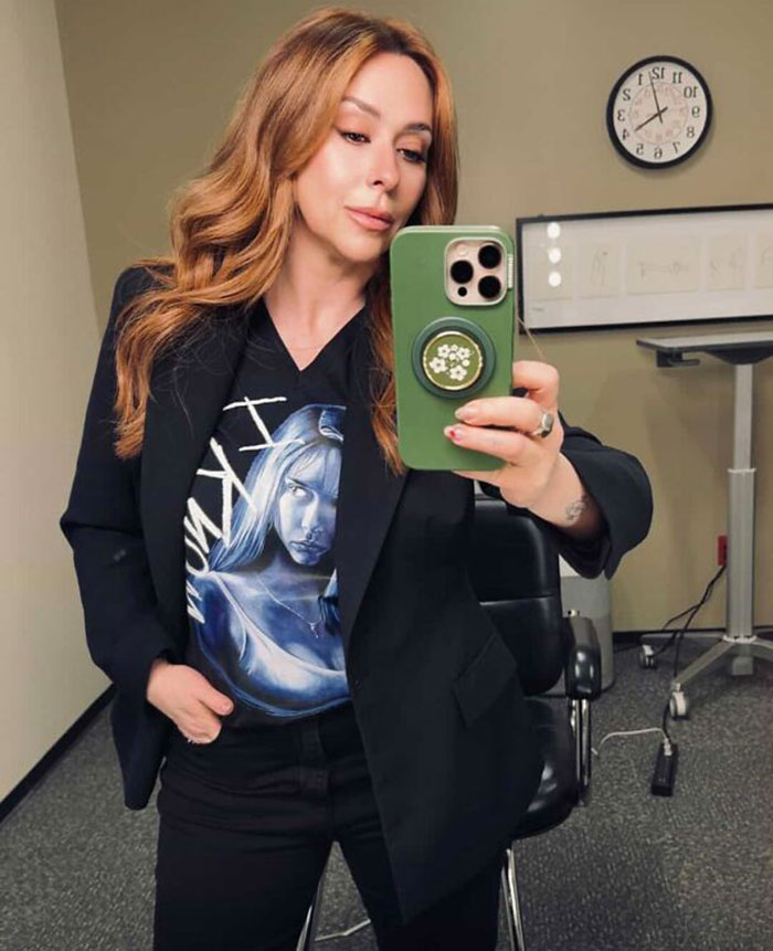 Sarah Michelle Gellar taking a mirror selfie in a black blazer and graphic tee, addressing premiere pose questions.