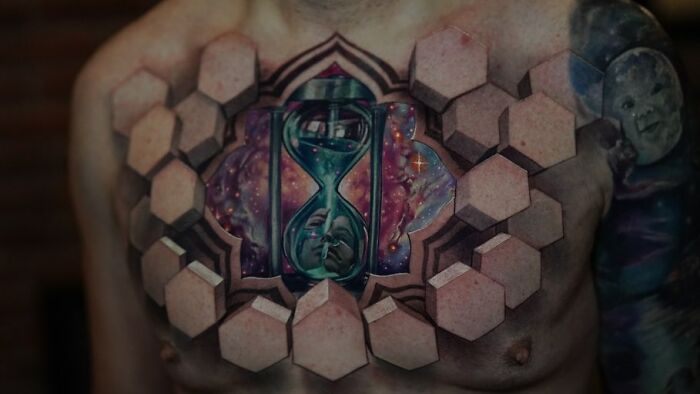 Chest tattoo with 3D hexagons forming a portal effect revealing a cosmic hourglass, showcasing 3D tattoos by Jesse Rix.