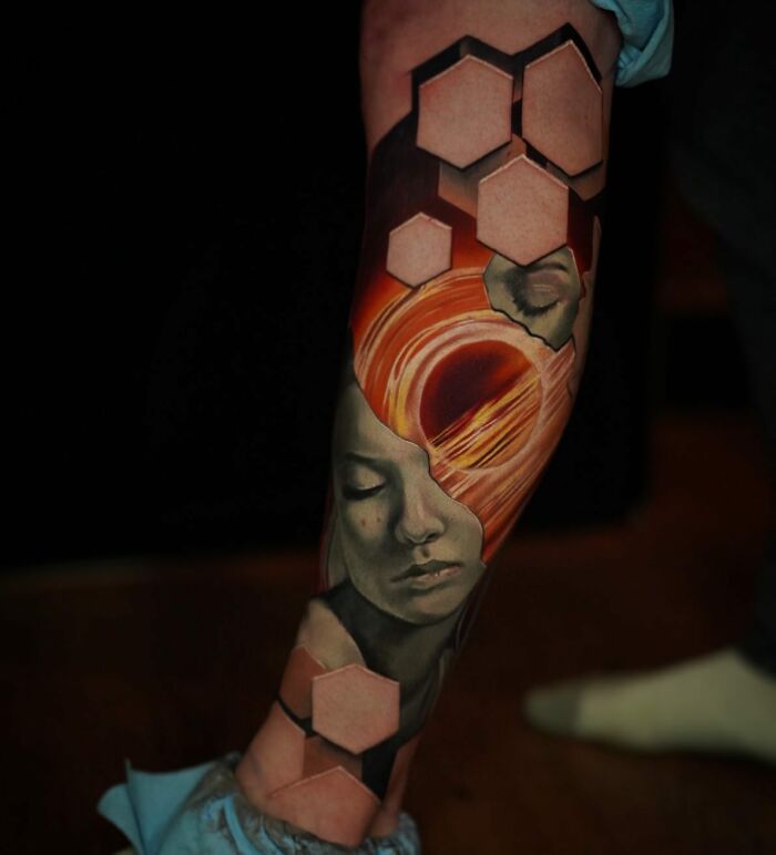 3D tattoo by Jesse Rix showing a surreal face and hexagonal shapes, creating a portal-like effect on the leg.