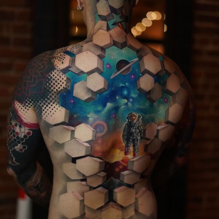3D tattoos by Jesse Rix featuring a space-themed portal with an astronaut and geometric hexagonal designs on a man's back.
