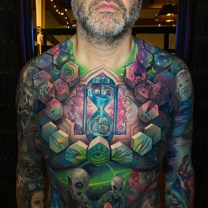 Colorful 3D tattoos by Jesse Rix featuring portals and cosmic designs covering a man's chest and arms.
