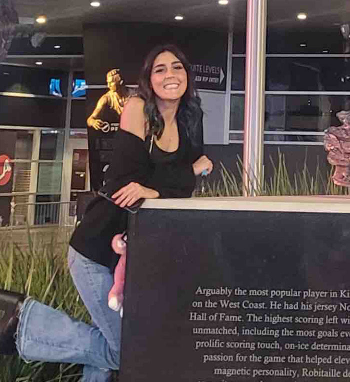 Young woman smiling beside a display, related to police update after 7-Eleven employee whose manager sat on her passes away.