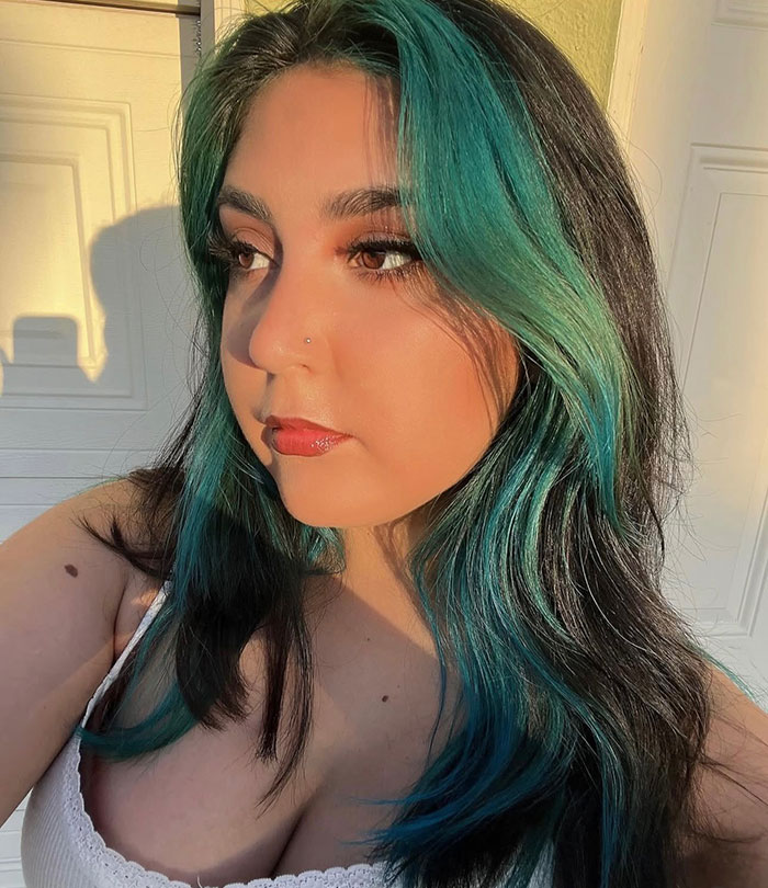 Young woman with teal and black hair posing in natural light, related to update on 7-Eleven employee passing from police report.