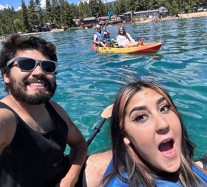 Two people smiling in a kayak on clear water with others kayaking nearby as police update after 7-Eleven employee passes