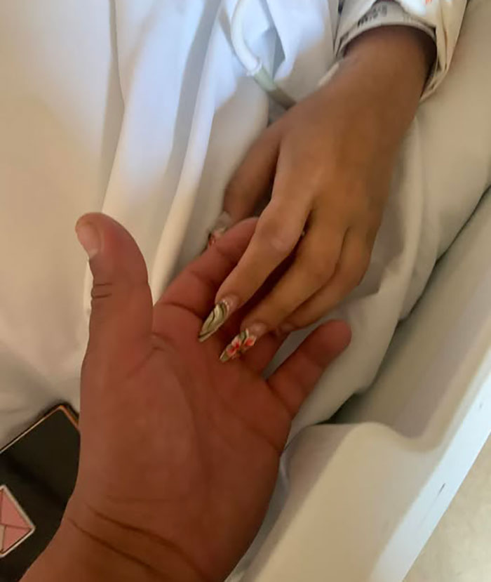 Hand holding with hospital bed sheets visible, related to 7-Eleven employee update police share after passing away