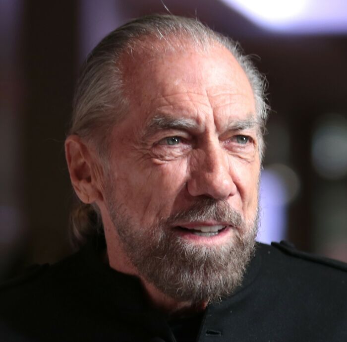 Older man with gray beard and long hair pulled back, representing a journey from poverty to super wealthy in a thoughtful expression.