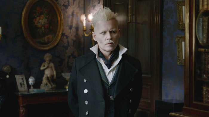 Johnny Depp as Grindelwald in a dark room scene from Fantastic Beasts, showing intense expression and period costume.
