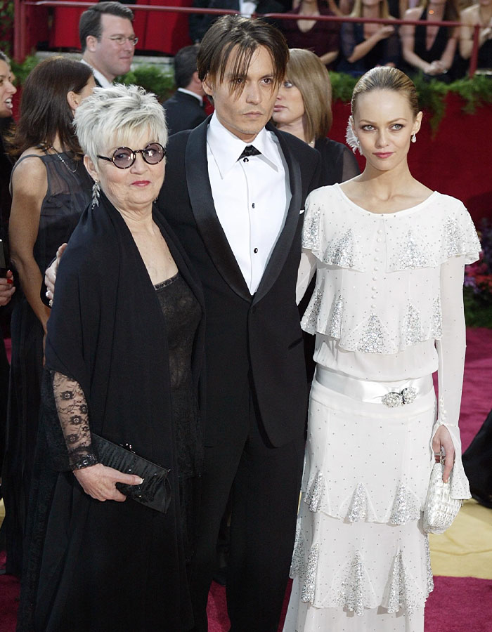 Johnny Depp on red carpet with woman and actress, recalling dark childhood with violent mom.