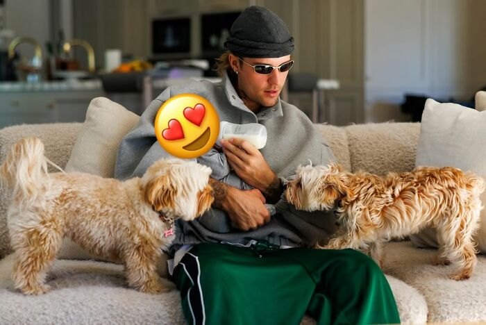 Justin Bieber sitting on a couch with two dogs, reflecting on marriage and mental struggles in new album SWAG.