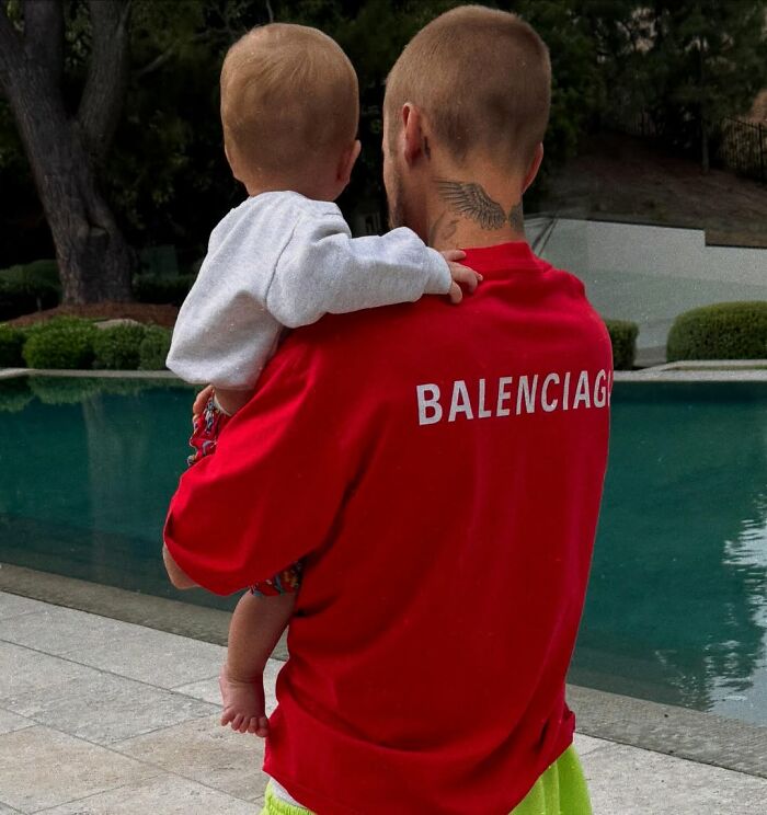 Justin Bieber holding a child by the poolside, reflecting on marriage and mental struggles in new album SWAG.