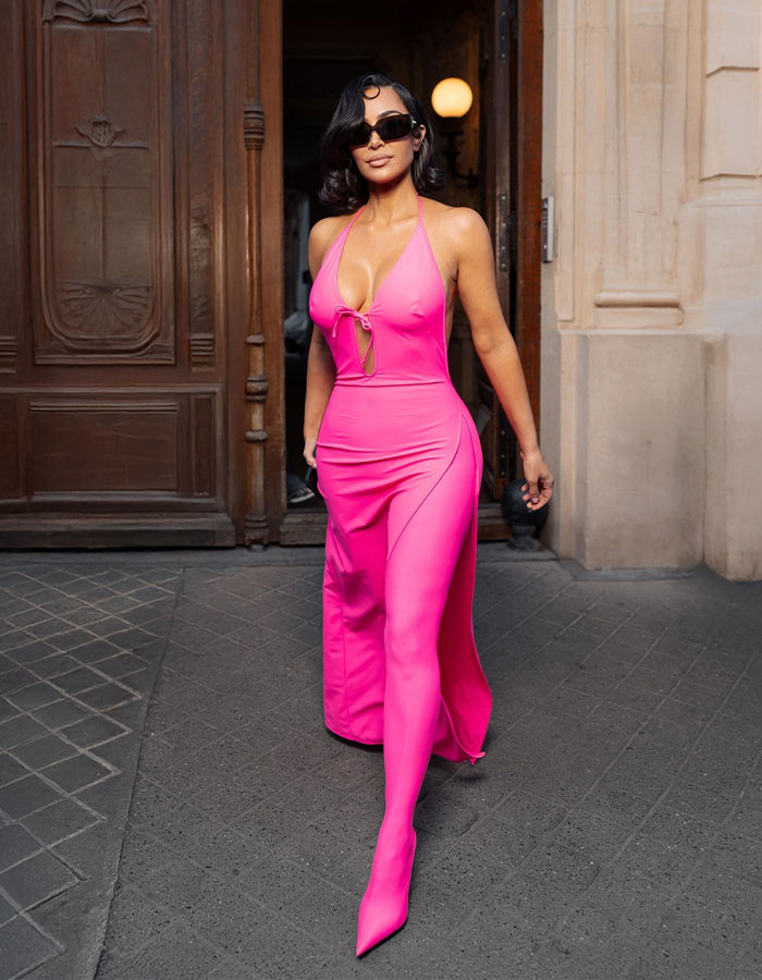Kim Kardashian in a bright pink dress and matching tights wearing a controversial brand at Paris Fashion Week. Kim Kardashian in a bright pink dress and matching tights wearing a controversial brand at Paris Fashion Week.