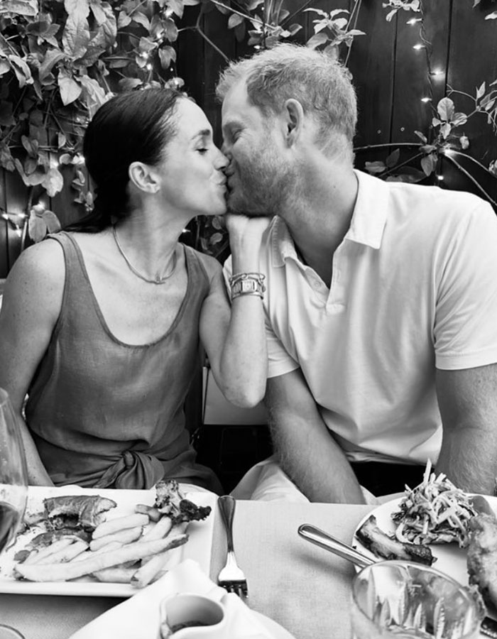 Prince Harry and Meghan Markle sharing a kiss during a meal, unrelated to King Charles praising William at Windsor Castle speech. Prince Harry and Meghan Markle sharing a kiss during a meal, unrelated to King Charles praising William at Windsor Castle speech.