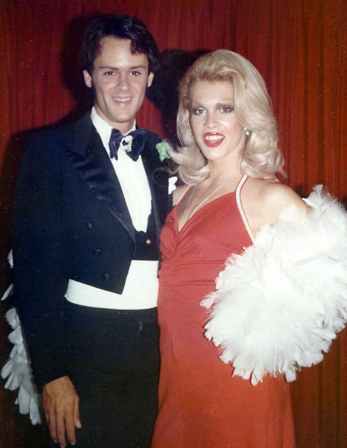 Woman in Florida wearing red dress and feather boa posing with a man in tuxedo, breaking barriers in the 1970s.
