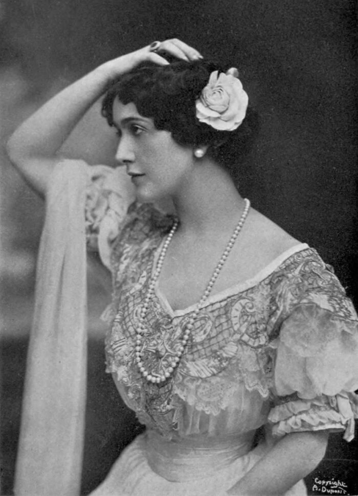Vintage century-old photo of a woman wearing a floral hair accessory and pearl necklace showcasing timeless beauty.