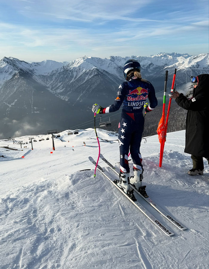 Professional skier Lindsey Vonn in full gear preparing to ski on a snowy mountain with snowy peaks in the background. Professional skier Lindsey Vonn in full gear preparing to ski on a snowy mountain with snowy peaks in the background.