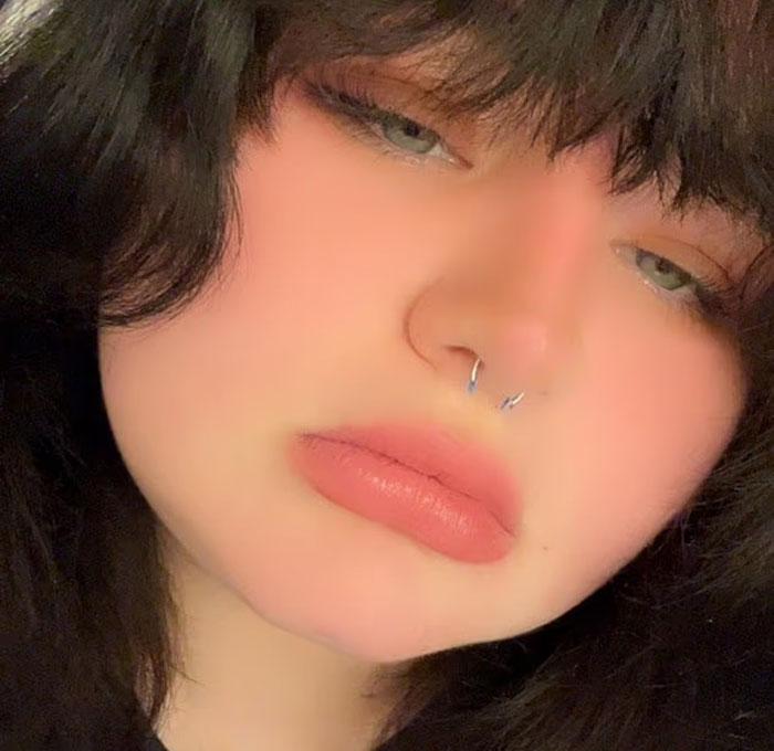 Close-up of a teen with dark hair and septum piercing, illustrating danger of being zapped by lightning inside house using phone. Close-up of a teen with dark hair and septum piercing, illustrating danger of being zapped by lightning inside house using phone.