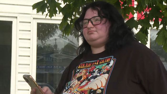 Teen holding phone outside house under tree, related to lightning zap incident caused by common mistake indoors. Teen holding phone outside house under tree, related to lightning zap incident caused by common mistake indoors.