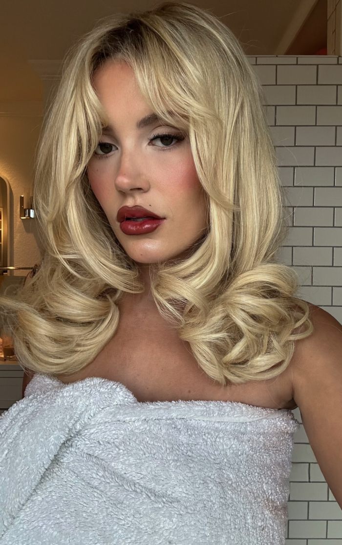 Woman with styled blonde hair wrapped in a towel, showing a shocked expression related to plastic surgery recovery. Woman with styled blonde hair wrapped in a towel, showing a shocked expression related to plastic surgery recovery.