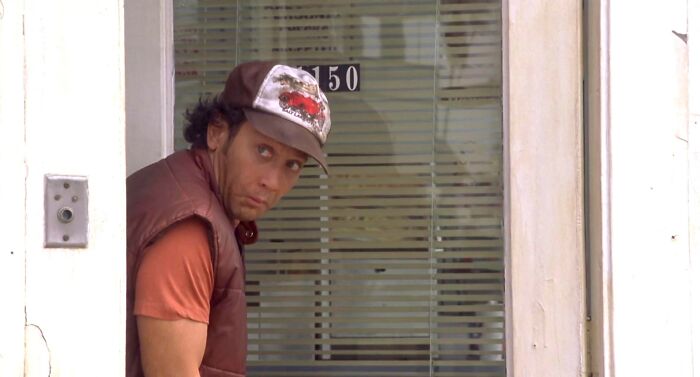 Man in a cap and vest peeking through a glass door, illustrating interesting rumors that turned out true.