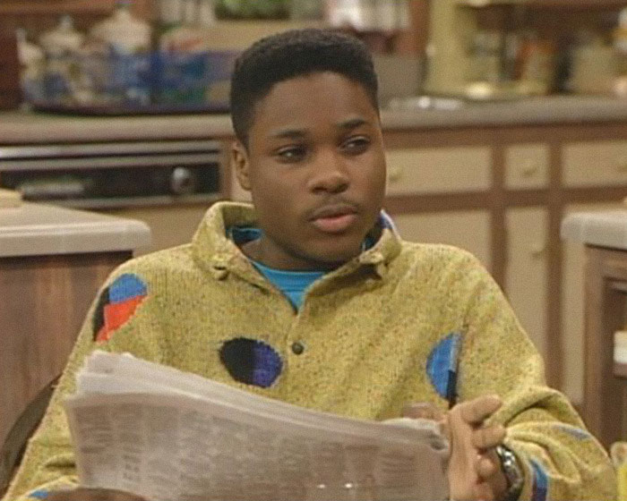 Young man in a colorful sweater reading a newspaper indoors, related to second victim revealed in tragic accident news.