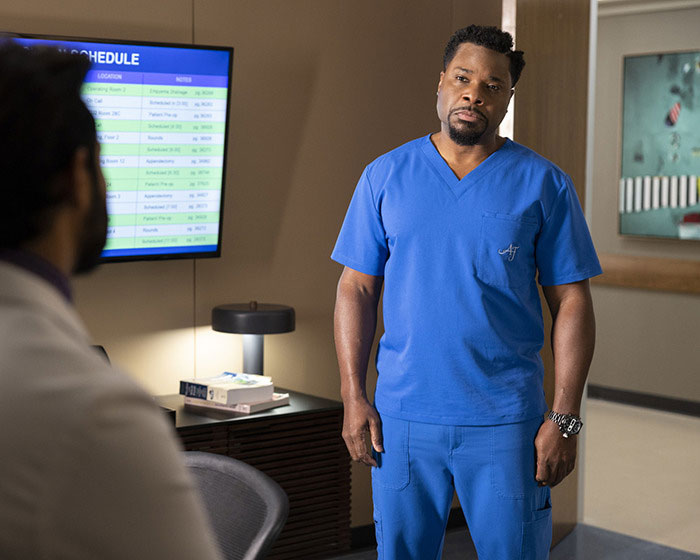 Man in blue scrubs talking to colleague in hospital room, related to second victim revealed in tragic accident.