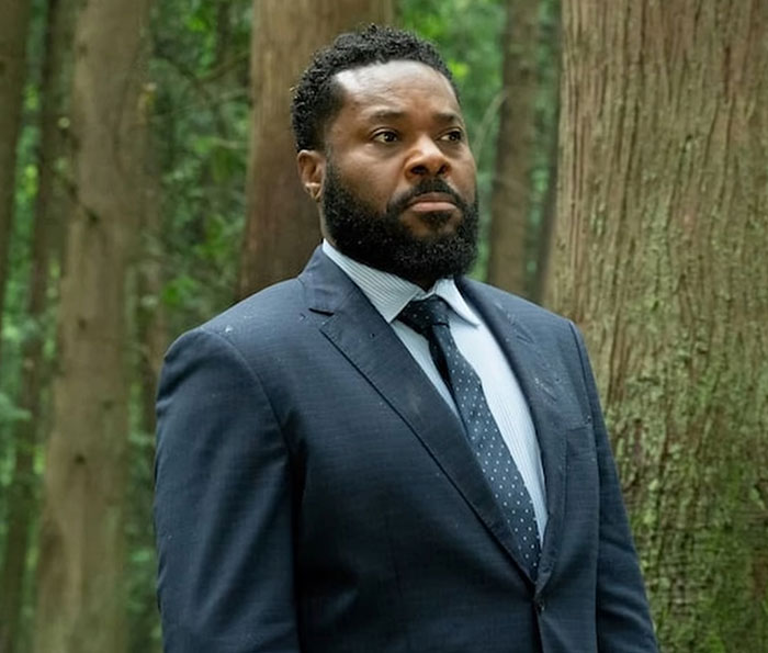 Man in dark suit and tie standing among trees, representing second victim revealed in tragic accident SEO topic.