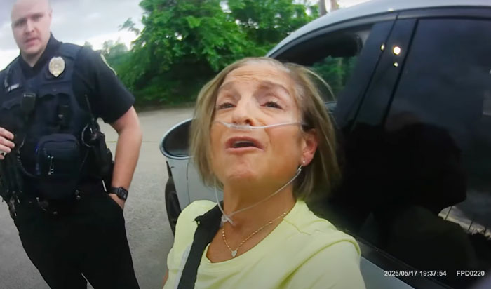 Olympic gold medalist Mary Lou Retton wearing oxygen tubes, interacting with police during a sobriety test outside a vehicle.