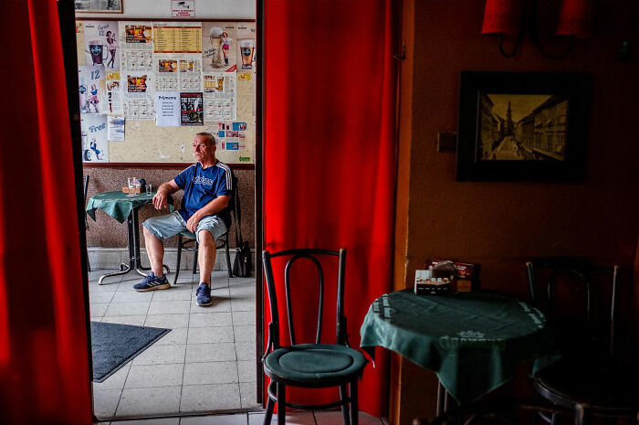 Man sitting alone inside a cafe, captured in an honest street moment showing the beauty of everyday life.