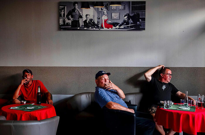 Three men sitting and smoking in a casual setting, capturing honest street moments showing the beauty of everyday life.