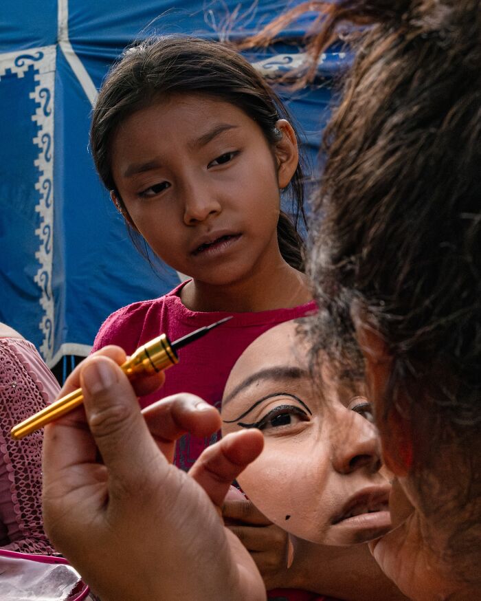 Young girl watching a street moment of makeup application reflected in a handheld mirror, capturing honest everyday life beauty.
