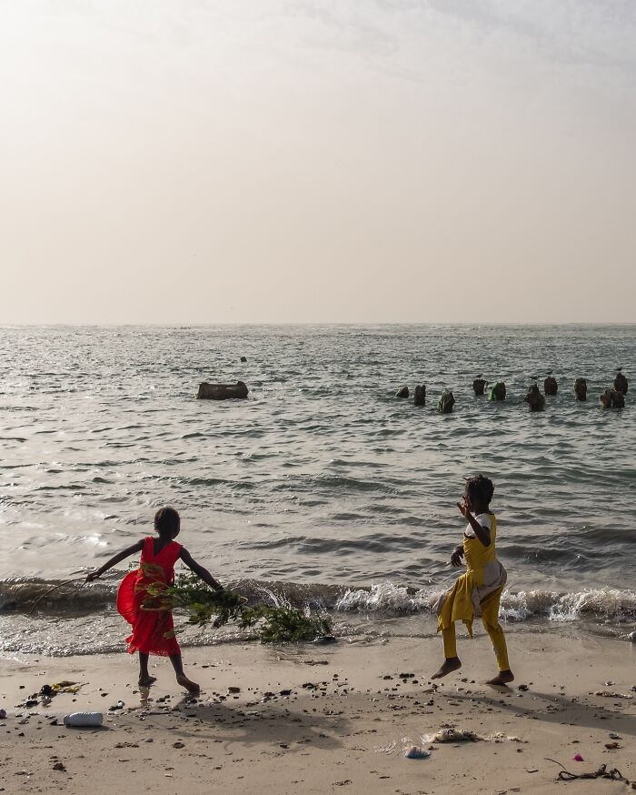 Two children playing on a beach at sunset, capturing honest street moments showing the beauty of everyday life.