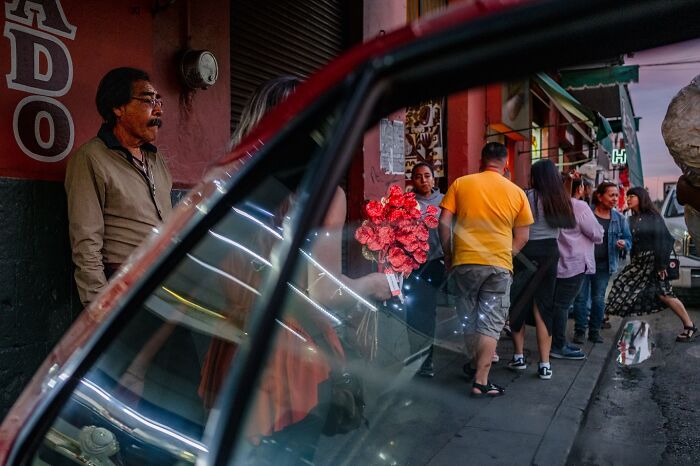 Street moments captured by photographer showing people waiting and interacting on an urban sidewalk in everyday life.
