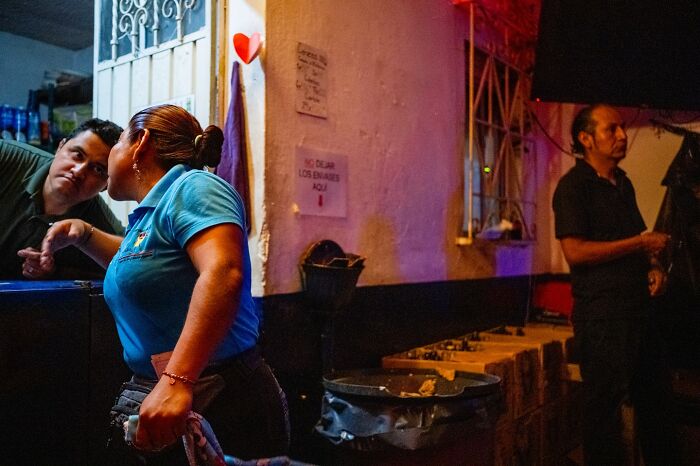 A candid street moment showing people interacting casually outside a building at night, capturing everyday life beauty.