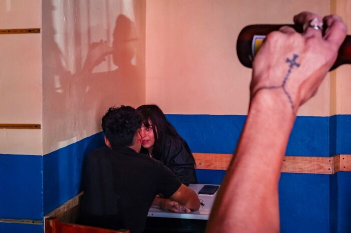 A photographer captures an honest street moment of two people sharing an intimate conversation in a colorful room.