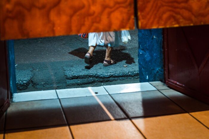 Person walking on a street at night, captured in an honest street moment showing the beauty of everyday life.