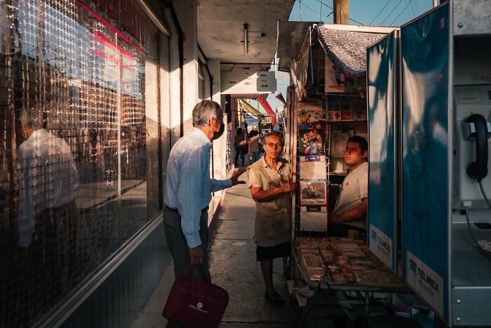 A photographer captures honest street moments of daily life showing people interacting in a lively urban setting.