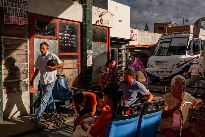 Busy street scene capturing honest street moments of everyday life with people waiting and walking in natural light.
