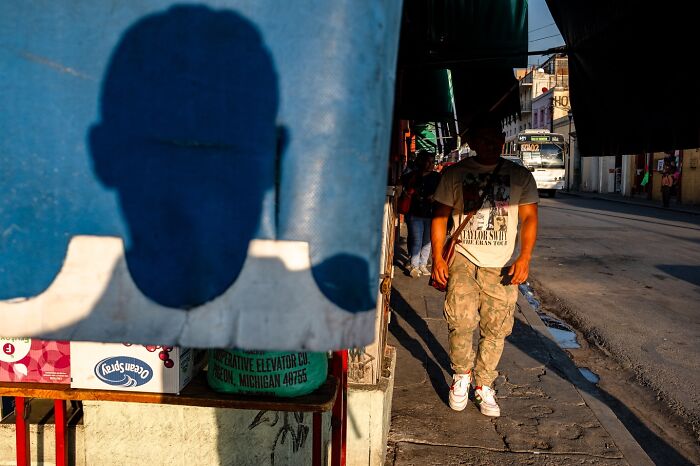 Street photography capturing honest moments of everyday life with a person walking on a sunlit urban sidewalk.