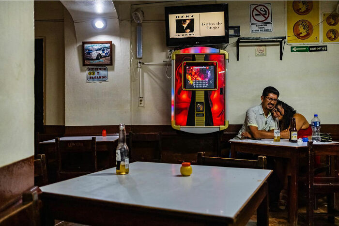 Couple sharing a tender moment in a cozy bar, captured as an honest street moment showing everyday life beauty.