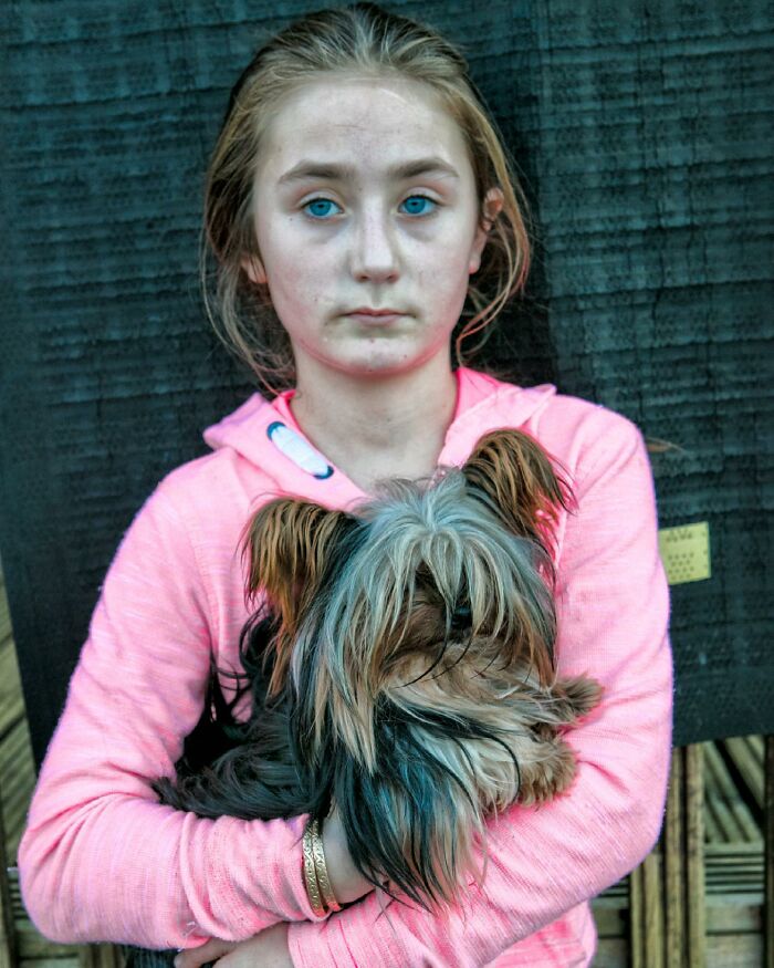 Irish Traveller kid with blue eyes holding a small long-haired dog, showing a bond growing up with animals.